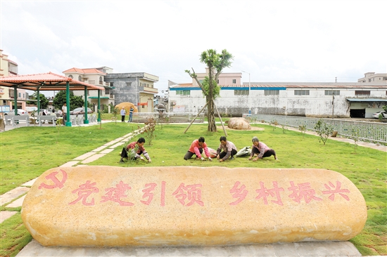 昆联村委会新建了红色文化公园，成为该村的新地标，图为几位村民忙着给公园草坪除杂草。