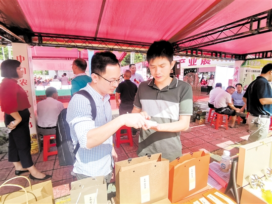 谢国良(右)向游客介绍企业产品。 谢国良(右)向游客介绍企业产品。