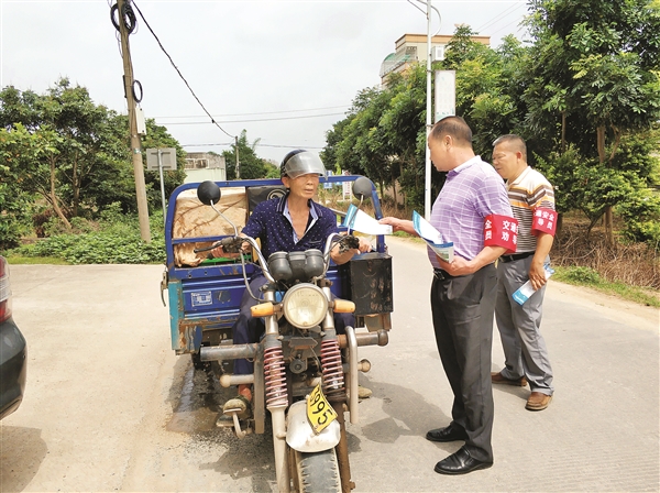     新光村交通安全劝导站劝导员在村道上向驾驶员发放交通安全宣传单。